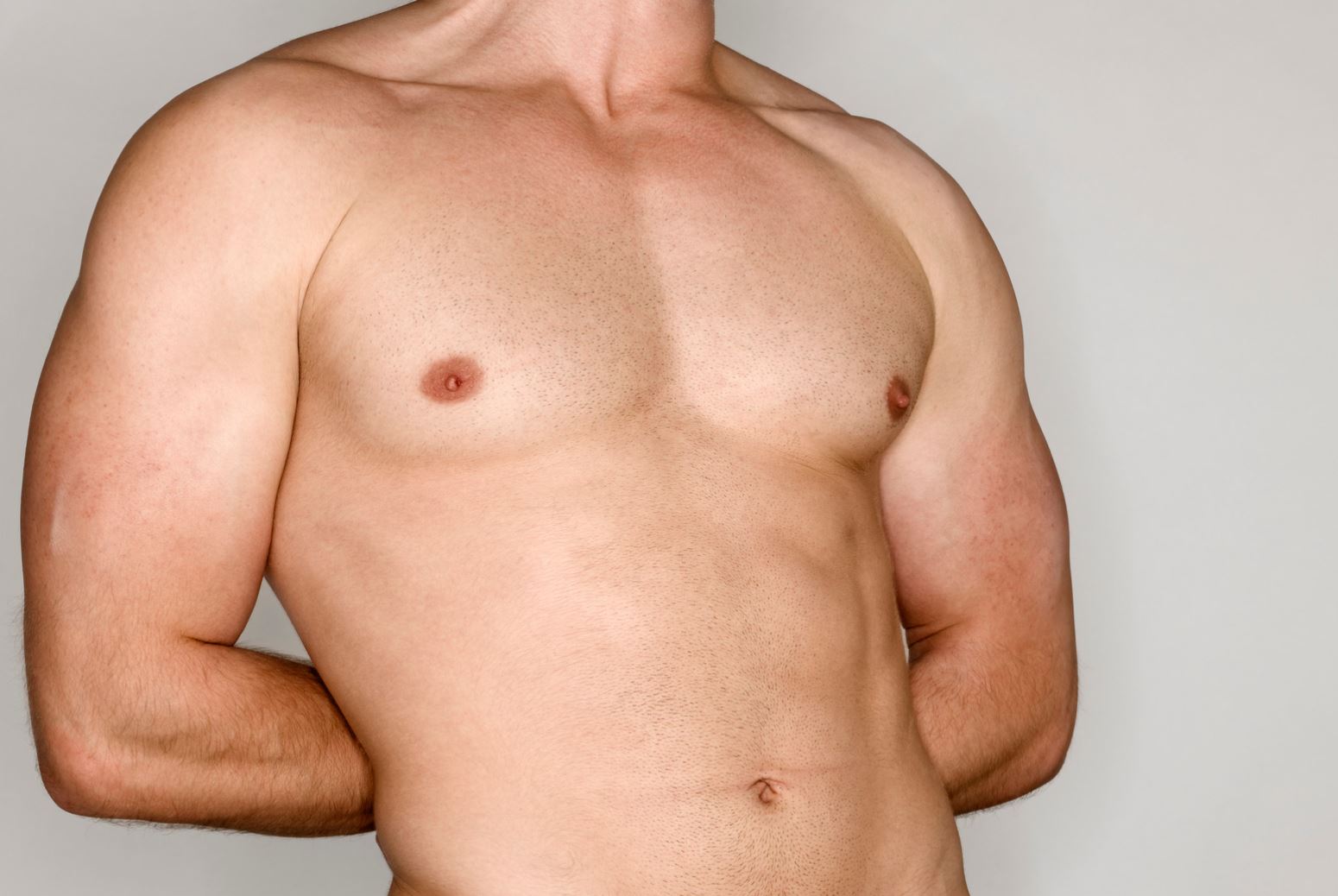 Muscular male torso showcasing defined chest and arms, demonstrating fitness and strength. The individual has a neutral expression and is positioned against a plain background, emphasizing the physique. This image is ideal for fitness-related content, health articles, or bodybuilding resources.